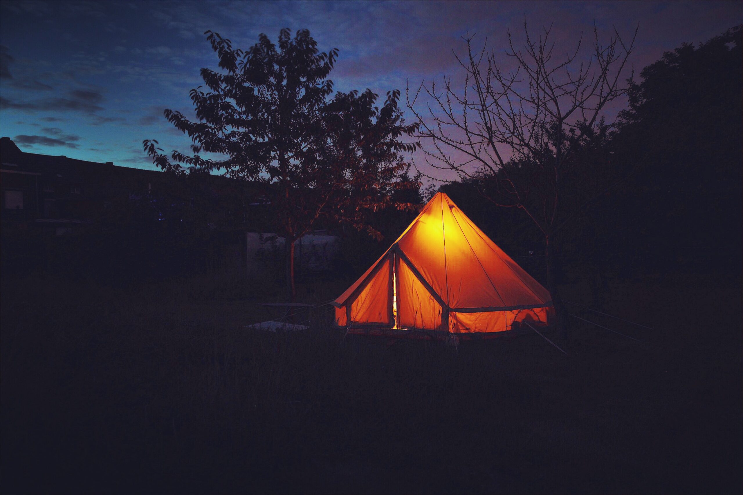 Verlichte tipi-tent in de avond op de tentenweide van De Mulkerij