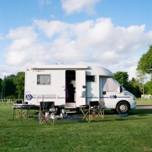 white and brown rv trailer on green grass field under white cloudy sky during daytime